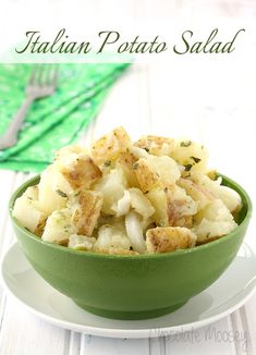 a green bowl filled with potato salad on top of a white plate