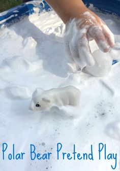 a child's hand is playing with play dough in a blue bowl filled with white foam