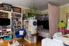 a living room filled with furniture and bookshelves next to a bed in a bedroom