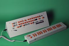 an electronic keyboard with orange knobs and wires attached to it on a green background