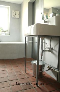 a bath room with a sink a tub and a clock on the wall above it