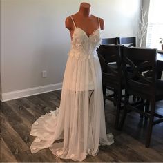 a wedding dress is displayed on a mannequin in front of a dining room table