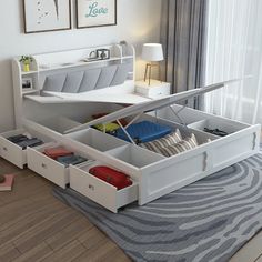 a white bed with drawers underneath it in a bedroom next to a window and rug