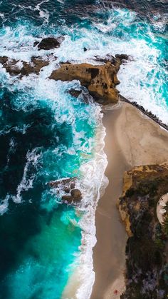 an aerial view of the ocean and beach with waves crashing in to shore, taken from above