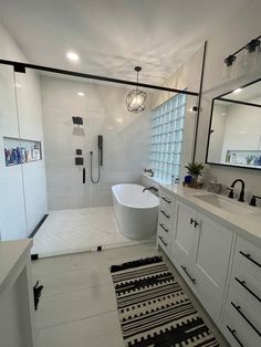 a white bathroom with black and white rugs on the floor in front of it