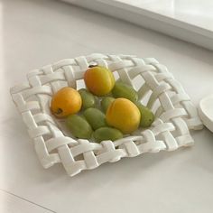 a white bowl filled with fruit on top of a counter