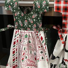 two christmas themed dresses hanging on a rack