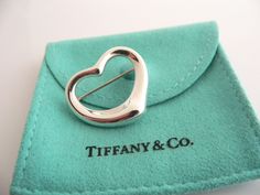 Overview:Offered for sale is a wonderful Tiffany and Co. Silver Peretti Open Heart Brooch/Pin.   The piece is made from substantial Tiffany silver formed into Peretti's classic Open Heart Heart shape.  In very good condition, this piece is one that you will turn to very often to jazz up your wardrobe.�  It is no longer produced, and thus makes a great addition for any Tiffany collector.   The piece has a perfectly working locking mechanism, and is fully hallmarked.Everyone needs a Signature Ti Rare Gifts, Heart Pin, Locking Mechanism, Heart Brooch, Gift Love, Tiffany And Co, Open Heart, Matching Necklaces, Blue Bags