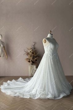 a white wedding dress on display in front of a mannequin headdress