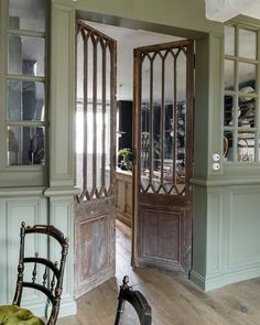 an open door leading to a dining room with green walls and wood trimmings