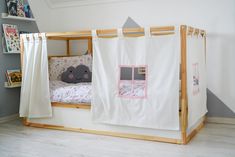 a child's bed with a tent on the top and curtains hanging from the bottom