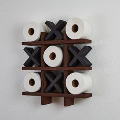 several rolls of toilet paper are arranged on a wooden shelf in front of a white wall