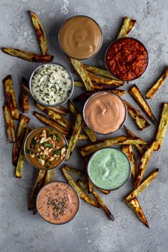 french fries with dipping sauces and condiments arranged in a circle on a gray surface