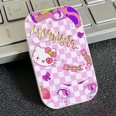 a cell phone case sitting on top of a computer keyboard with hello kitty stickers