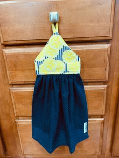 a yellow and blue top hanging on a wooden dresser next to a pair of black shorts