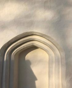 the shadow of a person standing in front of a white wall with arches and doorways