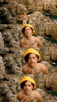 a man wearing a yellow hat standing on top of a rocky cliff next to the ocean