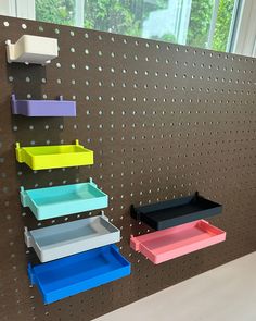 there are several shelves on the pegboard with holes in them and one shelf is painted different colors