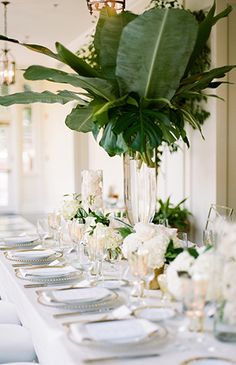 a long table is set with white flowers and greenery for an elegant wedding reception