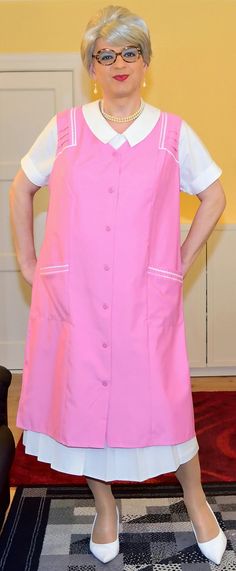 an older woman in a pink dress and white shoes standing with her hands on her hips