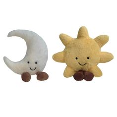 two small stuffed animals sitting next to each other on a white background, one with a smiling face and the other with a crescent