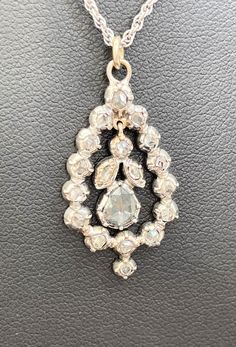 A Victorian diamond pendant with a platinum setting C1880. An outer ring of rose cut diamonds 15 in number and about 2mm of the diamond visible . The setting folds around the stone. In the centre, hanging by a gold loop and bale , are one round diamond, two smaller pair shaped diamonds and a large pear shape diamond approximately 6mm by 5mm.  All diamonds are rose cut. The central pear shape diamond has carbon inclusions visible with the magnifying glass. The chain is a modern addition., 16 inches long. The pendant is 31mm ( 1.2 inch ) into bale long and 16 mm Max, wide (0.64 inch) Total weight 7.4 gms Victorian Diamond Necklace With Single Cut Diamonds, Antique White Gold Diamond Necklace With Single Cut Diamonds, Diamond White Platinum Necklace With Rose Cut Diamonds, Platinum Diamond Necklace With Rose Cut Diamonds, Antique Silver Diamond Necklace With Diamond Accents, Victorian Diamond Necklace With Single Cut Diamonds For Anniversary, Antique Pendant Diamond Necklace With Accents, Antique Diamond Pendant Necklace With Accents, Victorian Silver Diamond Necklace With Single Cut Diamonds