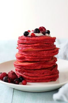 a stack of red velvet pancakes with berries on top