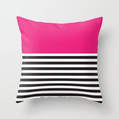 a pink and black striped pillow on a white wall