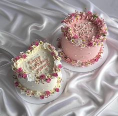 two birthday cakes with pink frosting and flowers on the top one has a happy birthday written on it