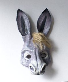 an animal mask with blonde hair and ears on it's head is hanging from the wall