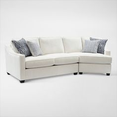 a white sectional couch with pillows on it's back and side facing each other