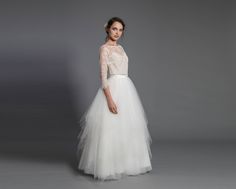 a woman in a white wedding dress standing on a gray background with her hands behind her back