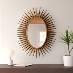 a mirror sitting on top of a wooden dresser next to a potted plant