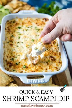 a hand dipping a piece of chicken and cheese into a casserole dish with tortilla chips