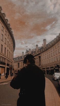 a man standing on the side of a street next to tall buildings