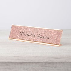 a pink glitter nameplate on a wooden table