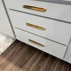 a kitchen with white cabinets and gold handles