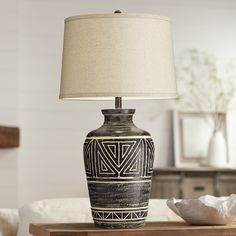 a black and white vase sitting on top of a wooden table next to a lamp