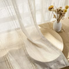 a white vase filled with flowers sitting on top of a table next to a window