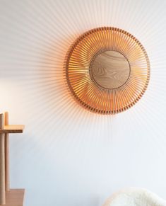 a wooden wall hanging on the side of a white wall next to a chair and table