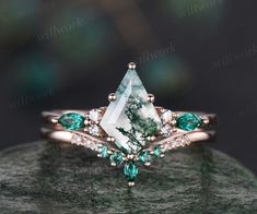 a green and white diamond ring on top of a rock with some diamonds around it