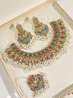 an elaborate necklace and earring set is displayed in a white box with gold trimmings