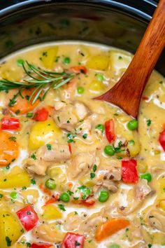 a wooden spoon in a slow cooker filled with chicken and veggie soup