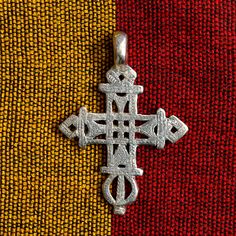 a cross on a red, yellow and black cloth with the word jesus written in silver