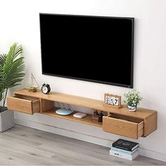 a flat screen tv mounted to the side of a wall next to a potted plant