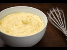 a white bowl filled with yellow batter next to a whisk