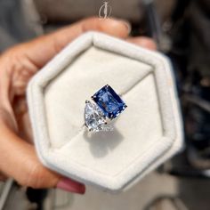 a person holding an engagement ring with a blue diamond in it's center piece