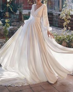 a woman in a white wedding dress standing on a brick walkway with her hands on her hips