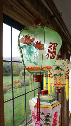 three chinese lanterns hanging in front of a window