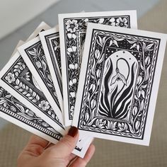 a person holding four cards in their hand with an intricate design on the front and back